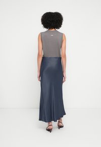 Bezroku kleita ar pelēku ribotu augšdaļu un plūstošu tams zila satīna apakšu. Pamanāma spīduma un nelielas A-līnijas siluets.