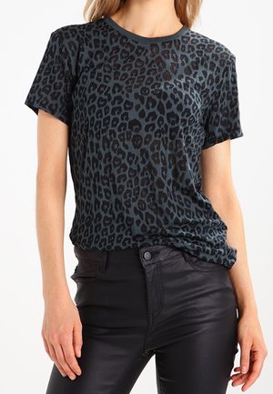 Kvinde iført en mørkegrå t-shirt med leopardprint og korte ærmer, der er stukket ned i sorte læderbukser med højtalje.