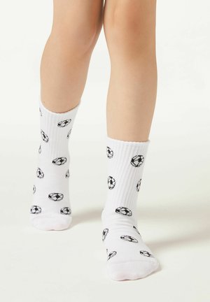 Hvide bomuldsocks med et gentaget mønster af sorte fodbolder. Ribbet struktur på toppen og standard længde til crew.