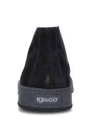 Stivaletti neri in suede con suola in gomma testurizzata e dettagli grigi. Cuciture decorative sul retro con il logo del brand visibile sul lato.