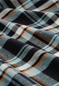 Baumwollflanellstoff mit einem Karomuster in Blau, Schwarz, Weiß und Orange. Weiche Textur mit einem welligen Fall.