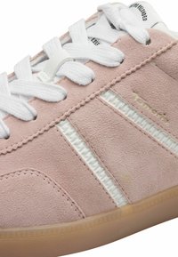 Sneaker in suede rosa con lacci bianchi, pannelli laterali testurizzati e suola traslucida. Un branding discreto appare vicino alla parte superiore.