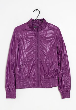 Giacca leggera viola con cerniera, collo alto, maniche lunghe, tasche laterali, polsini e vita elasticizzati, appesa a una gruccia nera.