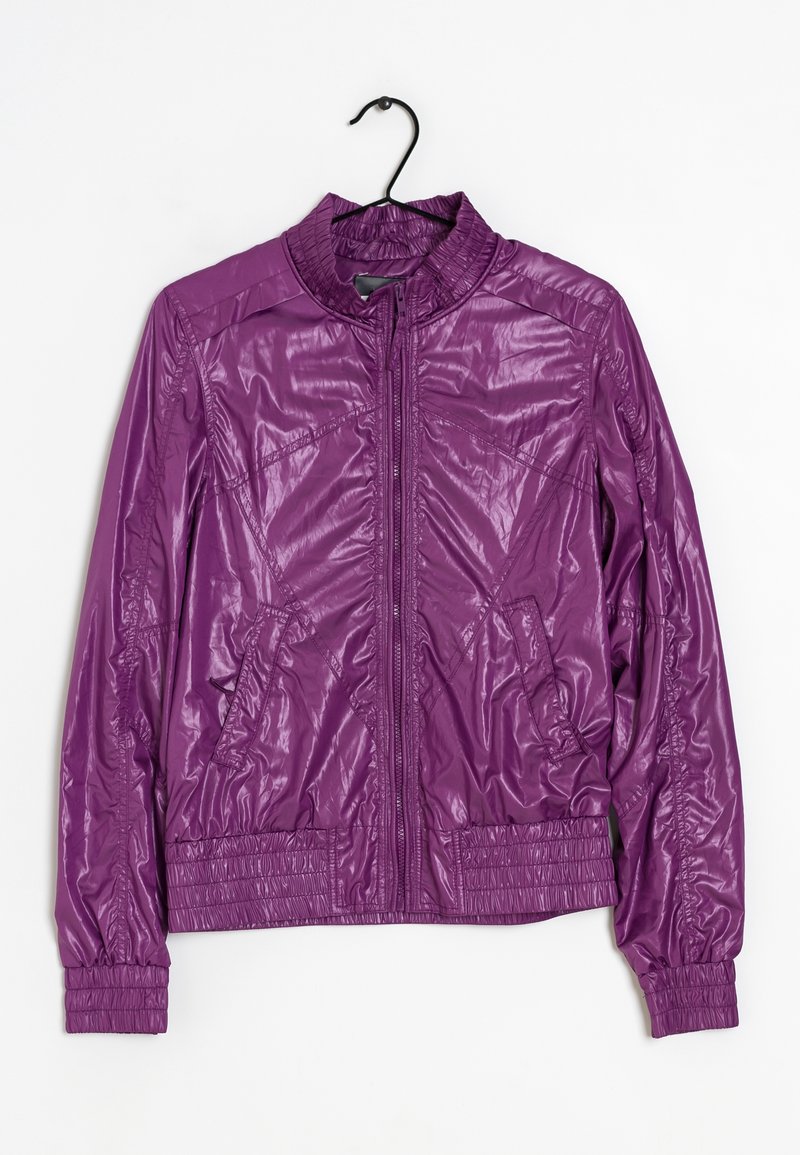 Veste légère violette zippée avec col haut, manches longues, poches latérales, poignets et ceinture élastiqués, suspendue à un cintre noir.