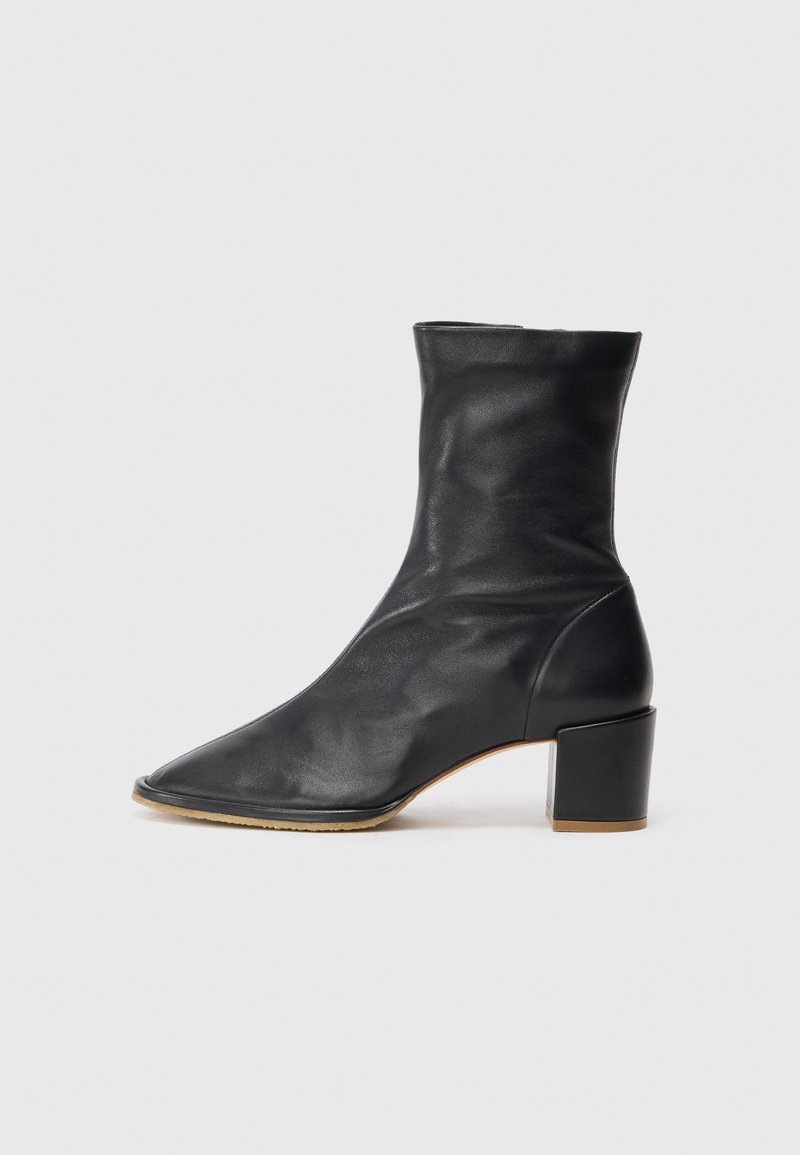 Schwarze Lederknöchelstiefelette mit spitz zulaufender Zehenpartie, tailliertem Schaft und robustem, quadratischem Absatz. Glatte Textur mit minimalen Nahtdetails.