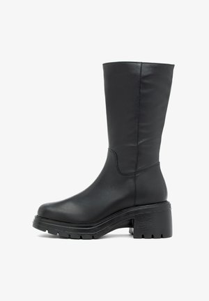Crne čizme do koljena napravljene od glatke kože. Imaju debeo platformu i okrugli vrh, s minimalnim detaljima šivanja.