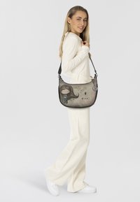 Borsa a spalla grigia con un design da cartone animato che presenta una ragazza, motivi floreali e la scritta "Dreams". Realizzata in materiale sintetico con una finitura testurizzata.