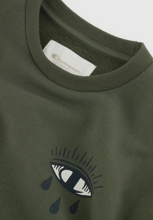 Olijfgroene t-shirt met een ronde halslijn, voorzien van een graphic van een oog en druppels eronder. Zachte katoentextuur, zichtbaar Champion-label aan de binnenkant.
