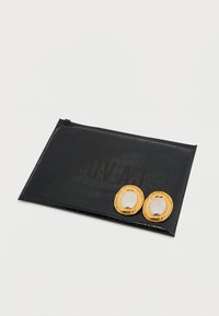 Mustast, reljeefse krokodillinaha mustriga käekott lukuga, ees kaks kuldset ovaalset detaili. Sile tekstuur, minimalistlik disain.