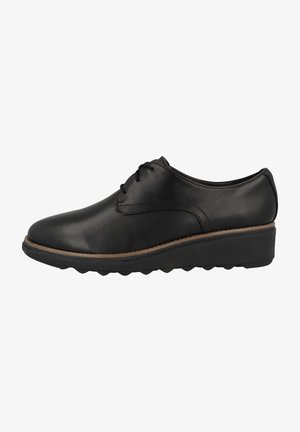 Chaussures en cuir noir avec un bout arrondi, un laçage et une semelle en caoutchouc texturée avec une légère plateforme.