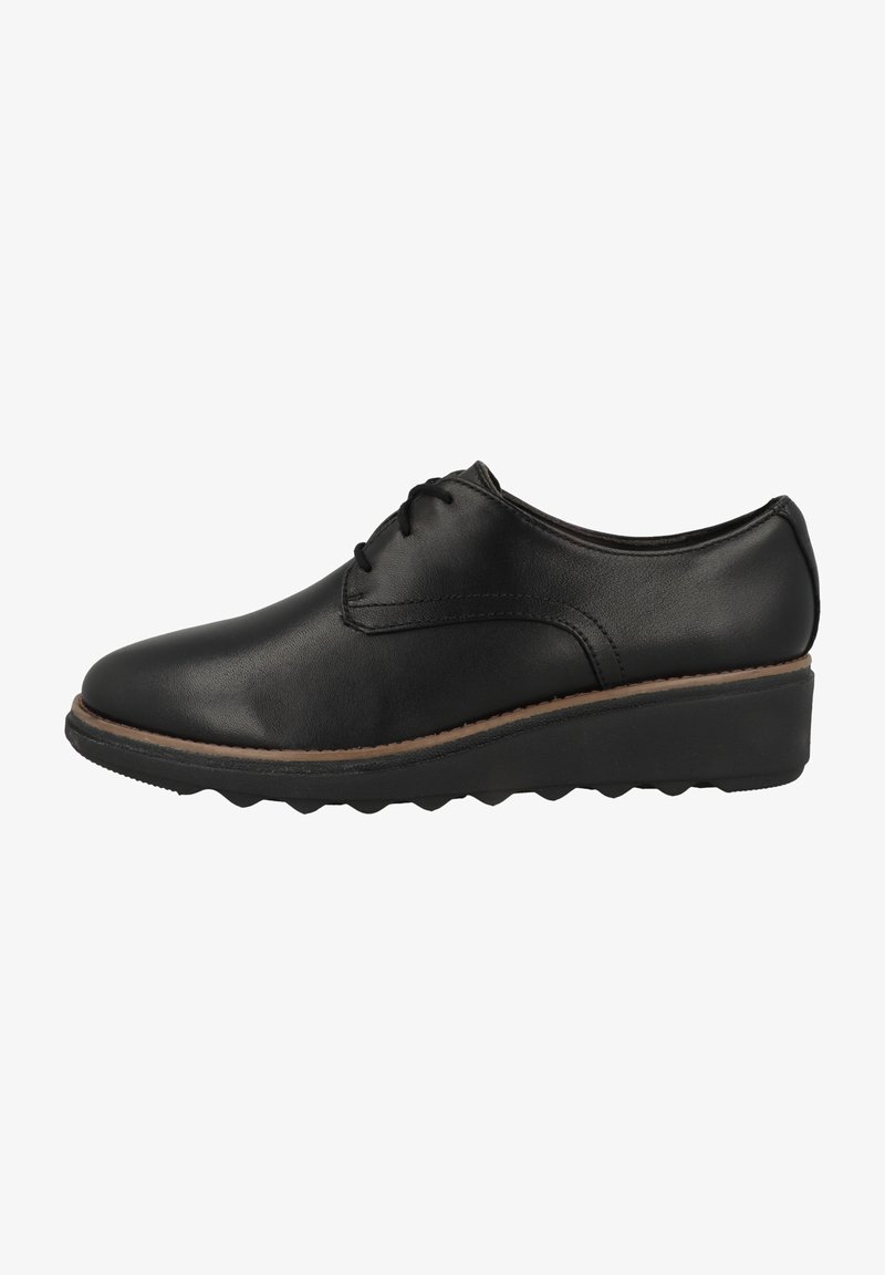 Chaussures en cuir noir avec un bout arrondi, un laçage et une semelle en caoutchouc texturée avec une légère plateforme.