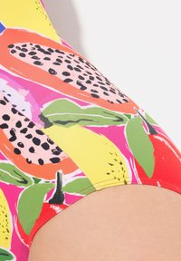 Tissu de maillot de bain coloré présentant un motif audacieux de fruits avec des tons de rose, jaune, vert et orange. Texture lisse, coupe extensible et coutures surpiquées.