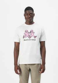 Grå bomulds t-shirt med et pink grafisk motiv af to tegneserie-løbere og teksten "Løbere er ikke normale" i sort. Kortærmet, rund hals.