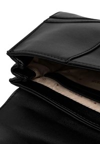 Borsa a mano in pelle nera con superficie testurizzata, dotata di doppia chiusura con cerniera e interno foderato beige con scomparti per carte.