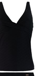Top de tankini negro con textura, escote en V cruzado y tirantes anchos, combinado con parte inferior a juego, aislado sobre fondo blanco.