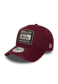 Gorra marrón con correa ajustable, que presenta un diseño de tela desgastada, una etiqueta rectangular que dice "Buffalo, NY" y la marca New Era.