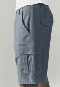 Pantalonii scurți cargo din material albastru marin au buzunare laterale și un buzunar la spate. Designul include un față plată și detalii cusute pe tiv.