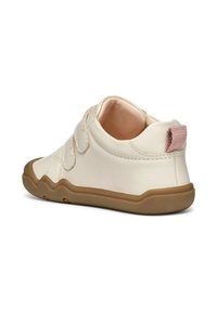 Zapato de cuero blanco con corte bajo, suela de goma marrón y pestaña de talón de tela rosa. Cuenta con dos correas de velcro para ajuste.