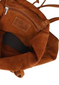 Interno di una borsa in suede marrone che mostra una tasca con zip e un'etichetta in pelle "Made in Italy" all'interno.