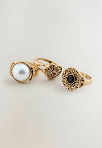 Set aus drei goldenen Ringen, darunter ein großer Perle, aufwendige Designs mit einem rosa Stein und ein strukturierter kreisförmiger Entwurf mit einem schwarzen Stein.