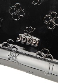 Pochette in pelle nera lucida con motivi floreali in rilievo, logo metallico "JOOP!" e cuciture decorative lungo il bordo.