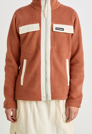 Oranje fleecejas met crèmekleurige accenten, volledige rits, hoge kraag, twee voorzakken en een merklogo op de linker borst.