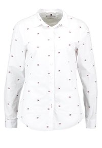 Camisa blanca de botones con un patrón bordado de pequeñas formas rojas y azules. Mangas largas con puños abotonados. Diseño de cuello clásico.