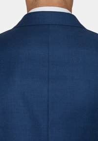 Granatowa marynarka z teksturowanej tkaniny, z klapami w kształcie notcha i pojedynczym rozporkiem z tyłu. Czyste, dopasowane linie.