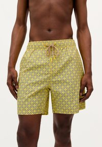 Costume de baie galben cu un model geometric în gri, având o talie elastică cu șnur bej. Tesătura pare netedă și ușoară.