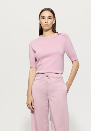 Light pink short-sleeve sweater made of soft fabric, featuring a round neckline and gold-button accents on the shoulder, paired with light pink trousers.