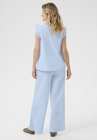 Set in tessuto a righe azzurro chiaro composto da una maglietta a maniche corte con dettagli arricciati e pantaloni a gamba larga, progettato per comfort e libertà di movimento.