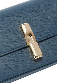 Pochette en cuir texturé bleu avec un fermoir rectangulaire doré. Présente une finition lisse et des détails en couture le long des bords.