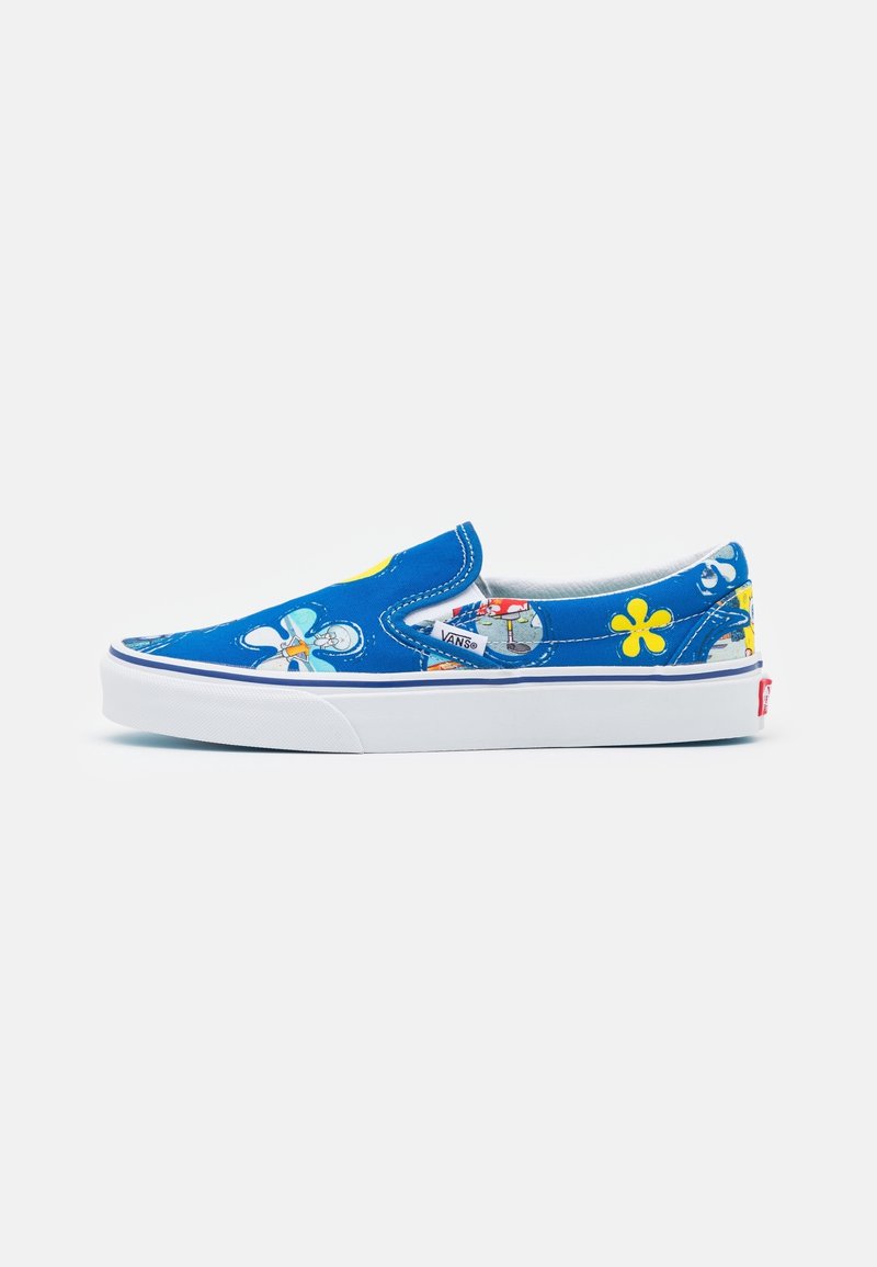 Chaussure en toile bleue à enfiler avec des motifs floraux et de dessins animés, semelle en caoutchouc blanche, col rembourré et étiquette du logo Vans sur le côté.