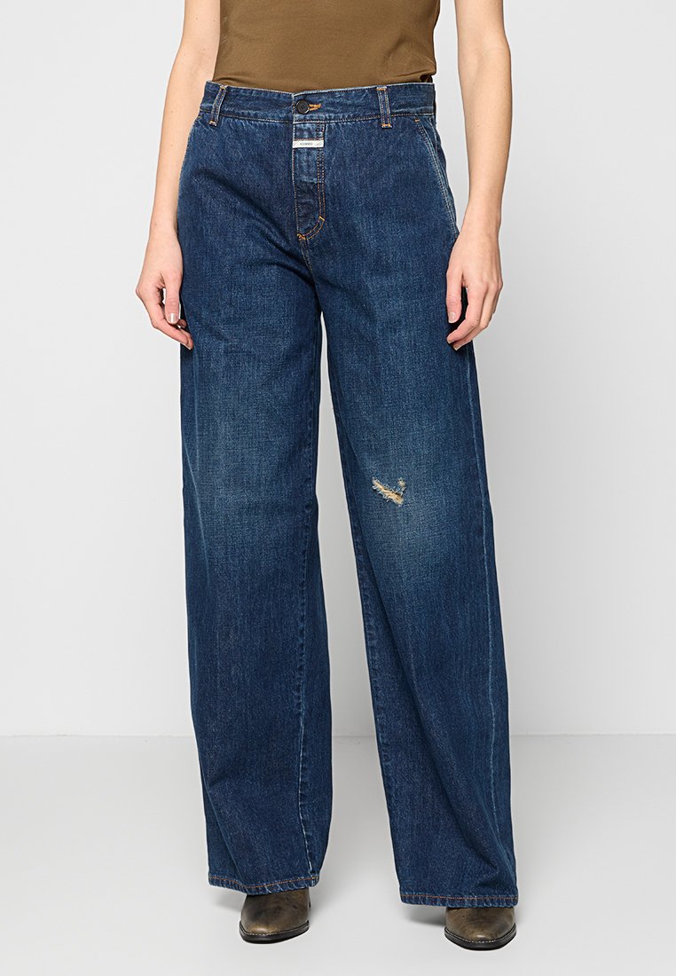 Niebieskie dżinsy typu wide-leg z jasnym praniem, z wyraźnymi przetarciami. Klasyczny design z pięcioma kieszeniami i metalowym zapięciem.