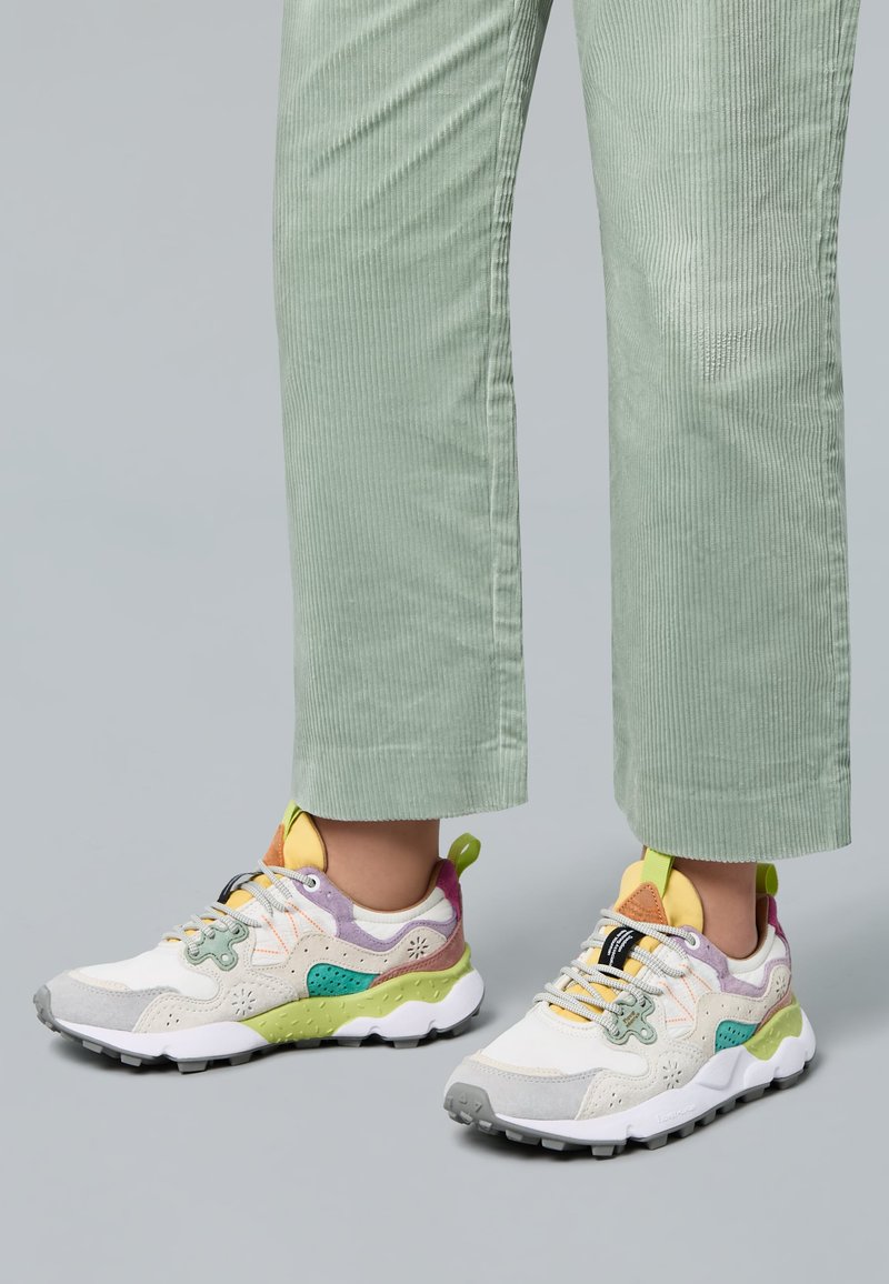 Weißer Sneaker mit mehrfarbigen Akzenten in Grün, Gelb und Lila. Verfügt über strukturierte Overlays, einen gepolsterten Schaft und eine Gummisohle.