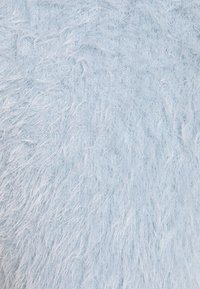 Tissu doux et duveteux bleu clair avec des fibres courtes et longues mélangées, créant une surface texturée et moelleuse.