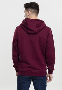 Bordeauxfarbener Hoodie mit einer großen, verstellbaren Kapuze. Verfügt über gerippte Bündchen und Saum, eine weiche Stofftextur und ein lässiges Design.