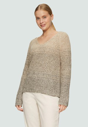 Beige gebreide trui met een V-hals, lange mouwen en een losse pasvorm. Gelaagd patroon en een lichte kleurverloop van licht naar donker. Gecombineerd met lichte broek.