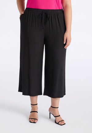 Zwarte, wijde culottes met een elastische tailleband, trekkoord en zijzakken. Gladde stof met een lichte textuur.