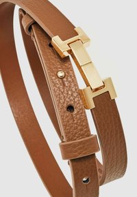 Rudas odinis diržas su tekstūruotu paviršiumi, kuriame yra auksinės spalvos aparatūros užsegimas ir reguliavimo skylutės juostos ilgyje.