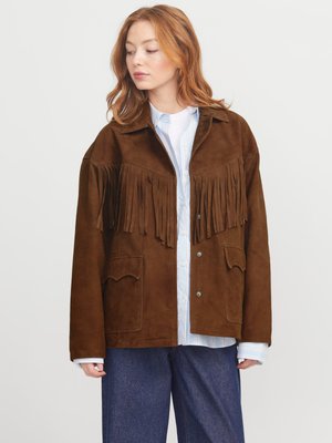 Veste en suede brun avec des franges, dotée d'un col, de deux poches avant et d'une coupe décontractée, portée par-dessus une chemise bleu clair.