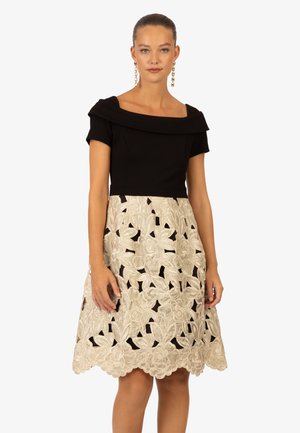 Schwarzes schulterfreies Kleid mit figurbetontem Oberteil und fließendem rockfarbenem Rock, der florale Stickereien und ausgeschnittene Details aufweist.
