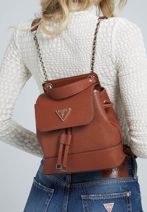 Sac à dos en similicuir marron texturé avec ferrures argentées, bretelles chaîne réglables et rabat avant avec détail logo.