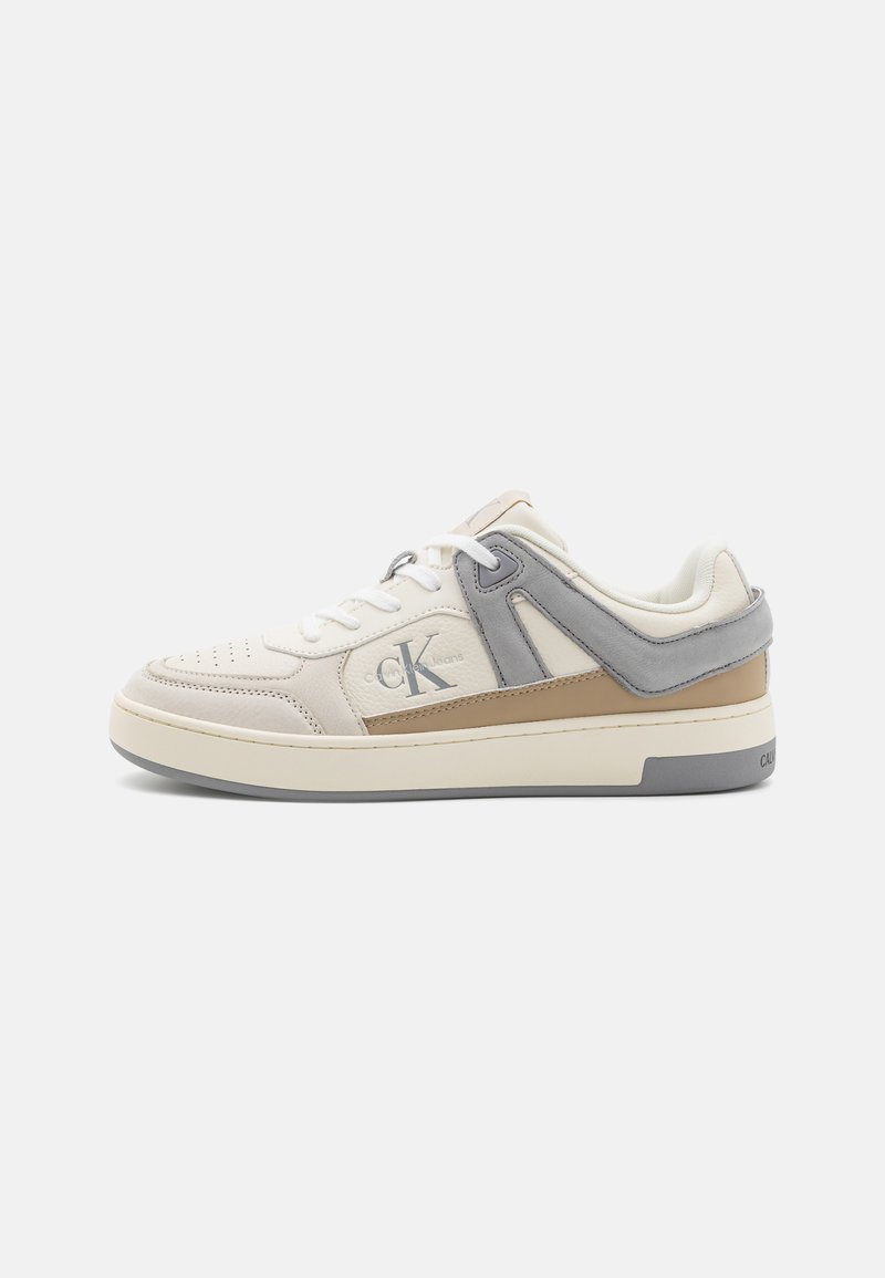 Sneakers Calvin Klein con tomaia in pelle bianca, dettagli in grigio e beige, punta tonda, lacci piatti e logo sul lato.
