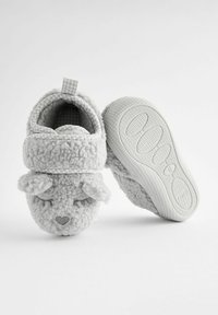 Chaussons en polaire gris avec un design de mouton, incluant des oreilles et des détails faciaux brodés. Semelle en caoutchouc blanc texturé et durable, avec une bonne adhérence.