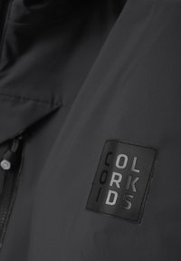 Melnas ūdensizturīgās jakas ar matētu apdari, regulējamu kapuci un teksturētu uzšuvīti ar "COLOR KIDS" logo kreisajā krūtī.
