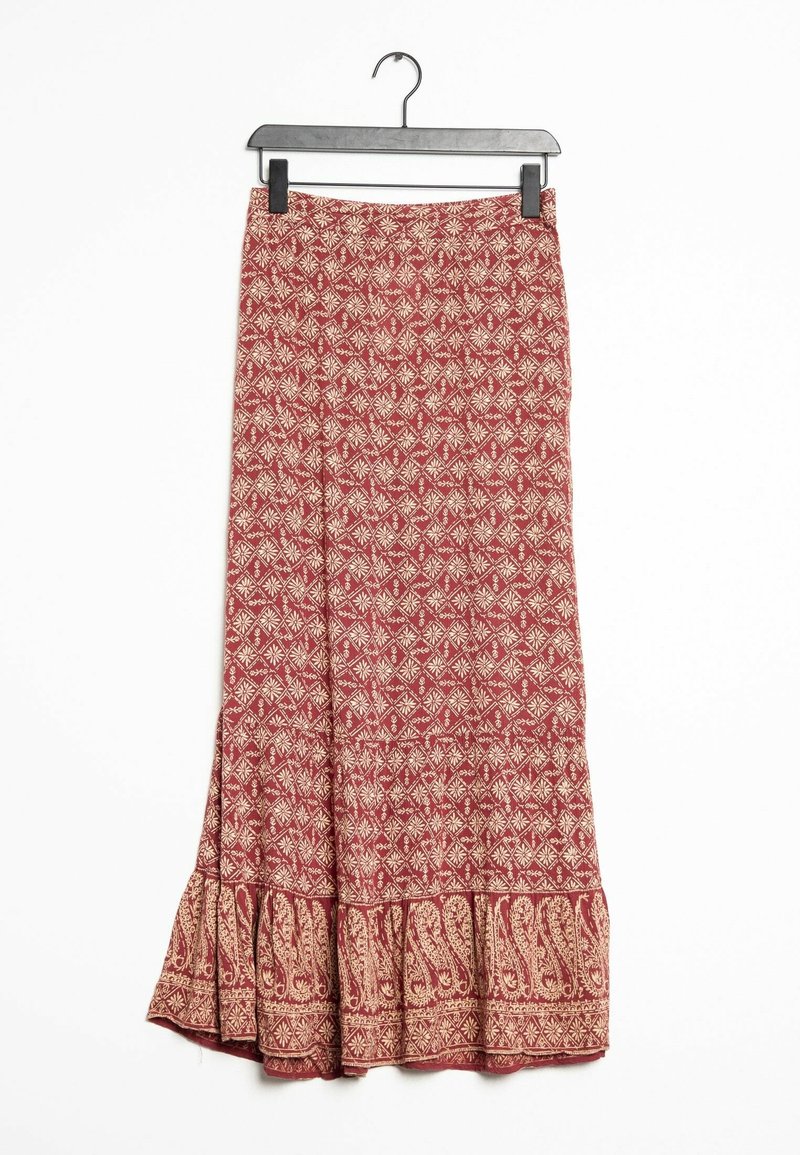Longue jupe rouge avec des motifs géométriques et floraux beiges suspendue à un cintre noir sur fond blanc.