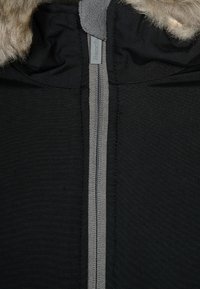Zwarte jack met een grijze rits en een met bont gevoerde capuchon. Het materiaal is glad met gestructureerde accenten rond de hals en rits.