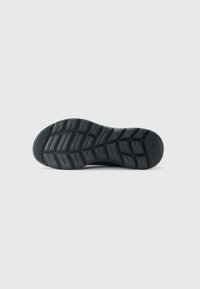 Semelle de chaussure noire avec un motif de relief texturé et des rainures de flexion, conçue pour l'adhérence et la flexibilité.