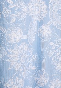 Tissu bleu clair avec des motifs floraux et de feuilles blancs. Présente des rainures verticales et des détails décoratifs tout au long du design.